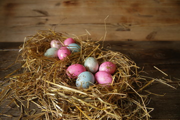 Colorful Easter eggs in a nest of straw on a rustic table with copy space for text