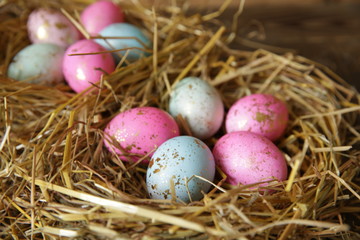 Colorful Easter eggs in a nest of straw on a rustic table. Close-up.