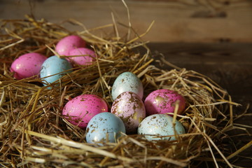 Colorful Easter eggs in a nest of straw on a rustic table. Close-up.