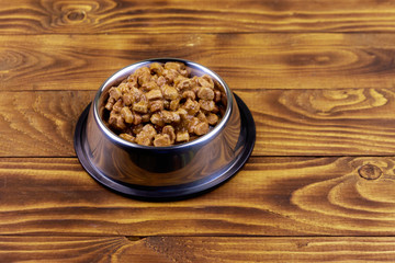 Canned food for cats or dogs in metal bowl on wooden floor