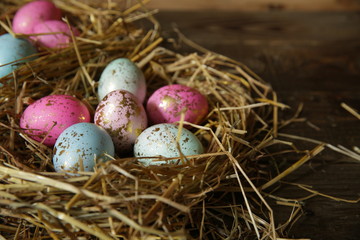 Colorful Easter eggs in a nest of straw on a rustic table
