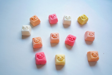 delicious square bright candy with smile on white background