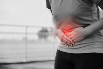 A woman is suffering stomach pain from running or workout, pain and colic is a frequent problem...