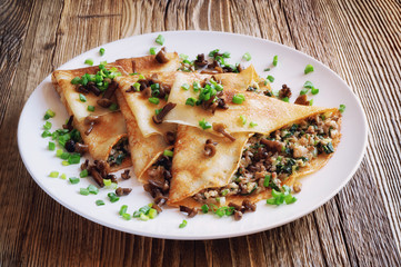 crepes with minced forest mushrooms, pork brisket, and fried onion decorated with green onion and honey agarics. toned