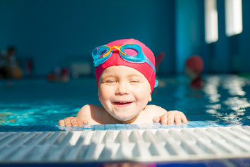 Child in a pool narrows eyes enjoying swimming