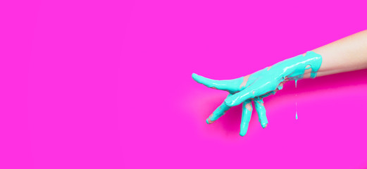 female hand in the paint flowing down the finger shows the direction on a colored background,...
