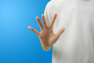 A white shirt man making stop gesture with his hand on blue background.