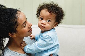 Woman holding her baby in room. Portrait of a baby boy.