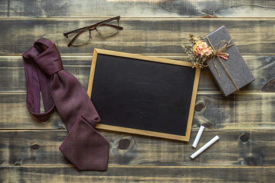 Flat lay image of gift box, necktie, glasses and blank space chalkboard. Father's day, Valentine's day and Labor's day concept. Top view with copy space for for your advertising text message.