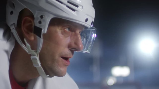 Close up face of determined male ice hockey player in helmet standing on rink and waiting for game to begin
