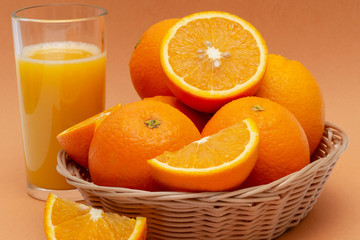 a basket of oranges and a glass of orange juice