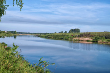Fototapeta premium Reflection of meadow in still river at summer