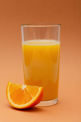 a glass of orange juice on an orange background with a slice of orange