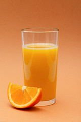 a glass of orange juice on an orange background with a slice of orange