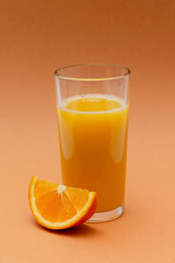 a glass of orange juice on an orange background with a slice of orange