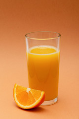 a glass of orange juice on an orange background with a slice of orange