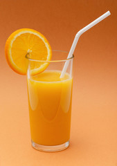 a glass of orange juice on an orange background with a straw and a slice of orange