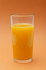 glass of orange juice on an orange background