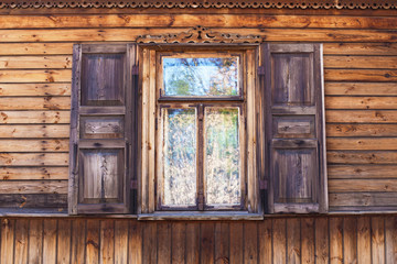 Rustic window in wooden village cottage house. Grunge weathered, abandoned brown wood wall background.