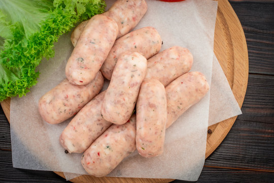 Fresh raw sausage on the wooden background, top view