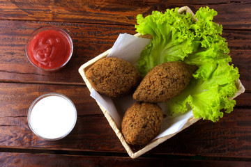 Fried kibbeh with tomato sauce in a basket, over rustic wooden table