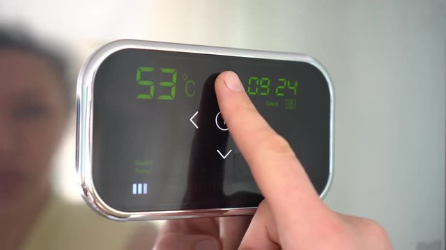 Adjust the thermostat setting. Smart Thermostat Heat Control. Touch Screen Programmable. The woman controls the temperature of the heating