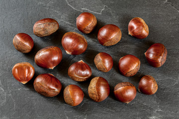 Flat lay photo, chestnuts on black slate board.