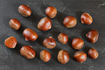 Chestnuts on black slate like board, overhead shot.