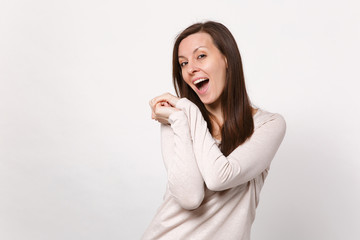 Portrait of cheerful young woman in light clothes holding hands together keeping mouth open isolated on white wall background in studio. People sincere emotions, lifestyle concept. Mock up copy space.
