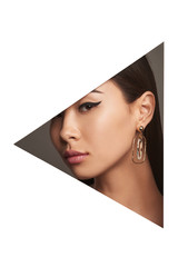 Cropped side half-turn geometric portrait of Asian woman with black flicks. The young girl is wearing long earrings with oval pendant inside, looking at the camera behind triangle-shaped foreground.