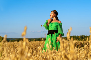 attractive brunette woman in wheat field in green dress