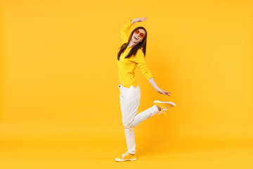 Fototapeta na wymiar Cheerful young woman in casual clothes, heart glasses looking aside spreading hands isolated on yellow orange wall background in studio. People sincere emotions, lifestyle concept. Mock up copy space.