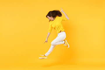 Fototapeta na wymiar Side view of excited young woman in summer casual clothes jumping, pointing index finger down isolated on yellow orange wall background. People sincere emotions, lifestyle concept. Mock up copy space.