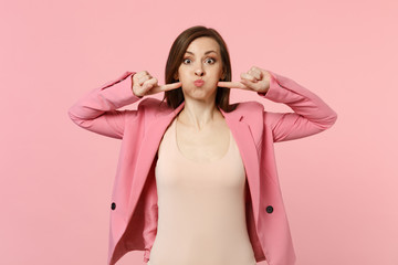Portrait of funny crazy young woman in jacket pointing index fingers on blowing cheeks isolated on...