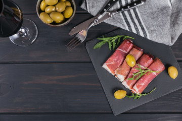 Black stone platter with slices of cured ham or Spanish jamon serrano or Italian prosciutto crudo