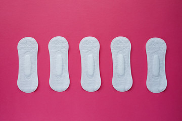 Feminine hygiene pad on a pink background. Concept of feminine hygiene during menstruation. Flat lay, top view.