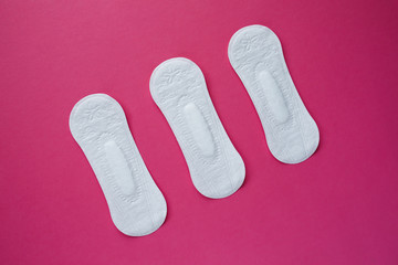 Feminine hygiene pad on a pink background. Concept of feminine hygiene during menstruation. Flat lay, top view.