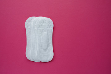 Feminine hygiene pad on a pink background. Concept of feminine hygiene during menstruation. Flat lay, top view.