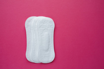 Feminine hygiene pad on a pink background. Concept of feminine hygiene during menstruation. Flat lay, top view.