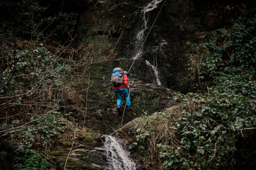 Young man dulfers down the mountain with waterfall