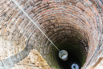 Plastic bucket in old ancient groundwater well.