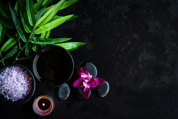 Obraz na płótnie Canvas Thai Spa. Top view of hot stones setting for massage treatment and relax with purple orchid on blackboard with copy space. Green leaf with black stones pile for spa therapy. Lifestyle Healthy 