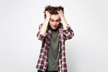 Portrait of shocked exhausted young man in casual clothes looking down putting hands on head isolated on white wall background in studio. People sincere emotions lifestyle concept. Mock up copy space.