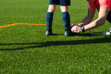 Adult referee tying a shoe to a child soccer player