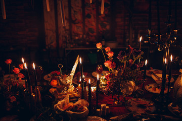 Table wedding decor. Pink, blue and red flowers bouquet and candles in bottles.