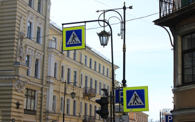Pedestrian crosswalk signs on busy downtown city street with buildings on background. Crossing...