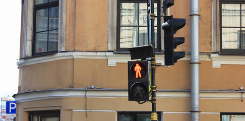 Red traffic light on city street background. Pedestrian crosswalk stop signal showing a standing...