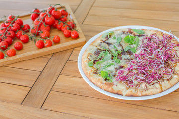 Pizza with tomatoes, mozzarella cheese, black olives and basil. Delicious italian pizza on wooden pizza board. Table top view