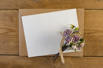 Craft brown envelope with dry flowers on wood background.