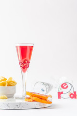 red non-alcoholic aperitif with chips and slices of orange on a white background 